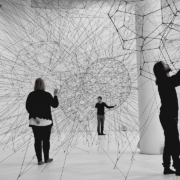 Kunstinstallation mit mehreren Menschen in einem weißen Raum mit visualisierten Strukturen