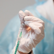 Foto, das eine Hand mit Spritze und Impfstoffampulle zeigt