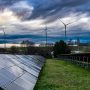 Solaranlage auf grüner Wiese im Hintergrund Windräder