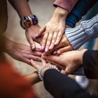 Hände verschiedener Menschen, die übereinander liegen und einen Kreis bilden